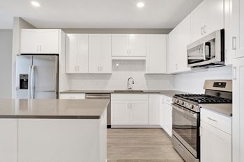 An all white kitchen with stainless steel appliances and white cabinets